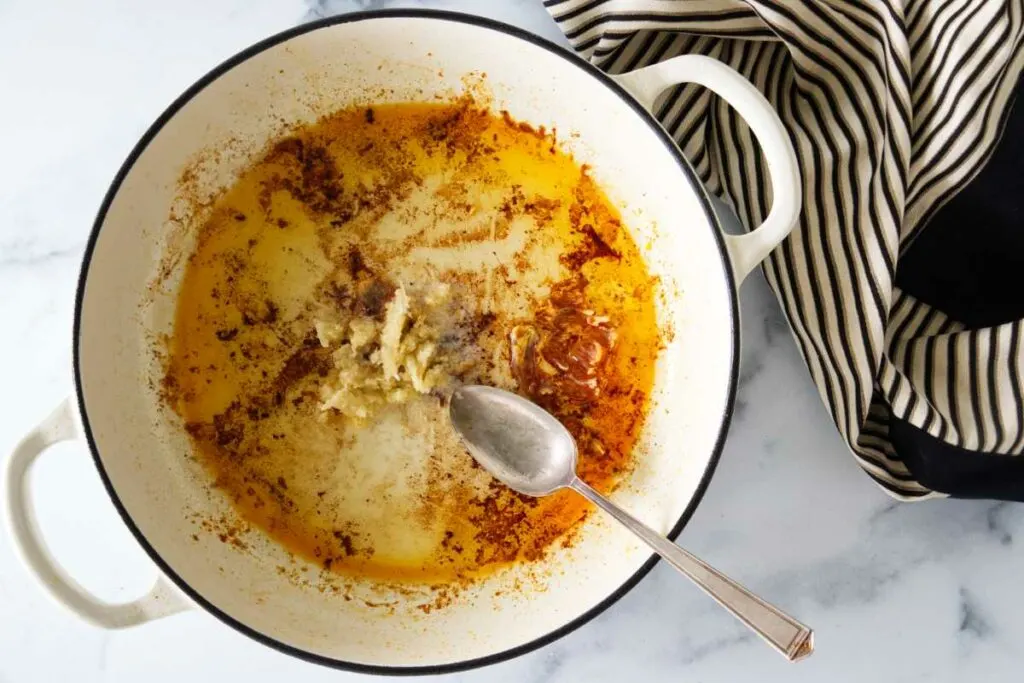 A pan with the oil from searing paprika chicken, grated garlic and a tablespoon.