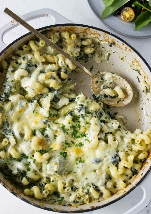 A spoon in a skillet filled with a pasta bake.