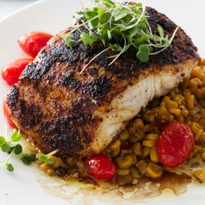 a serving of blackened halibut on a bed of chipotle corn salsa and sauteed tomatoes.