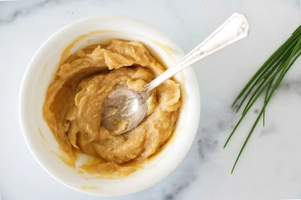 A dish with the miso and butter combined with a spoon. Fresh chives on the side.