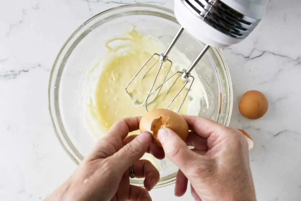 Cracking eggs into a mixing bowl.