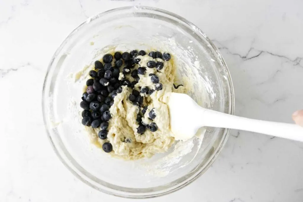 Folding blueberries into muffin batter.