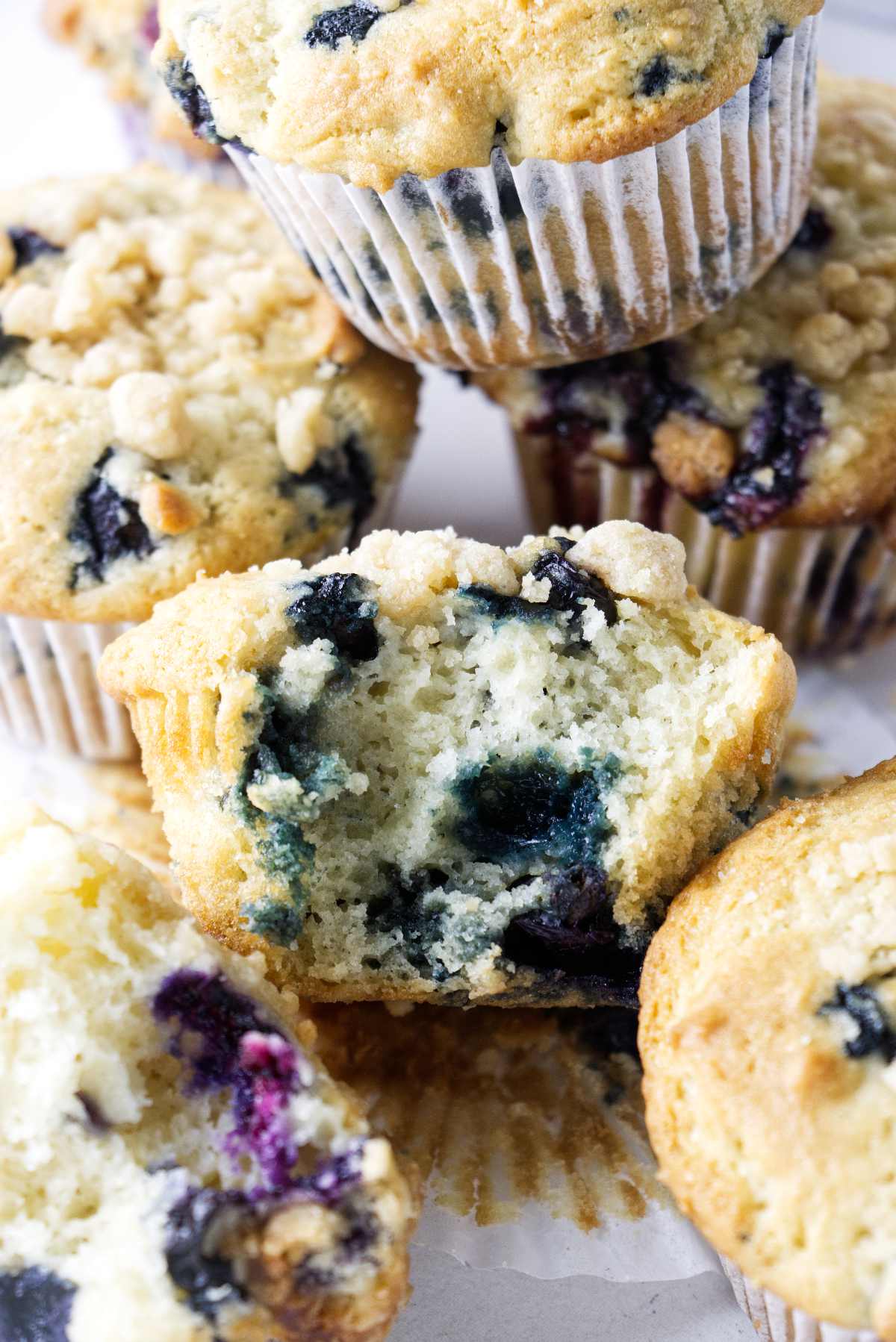 A partially eaten blueberry muffin surrounded by more muffins.