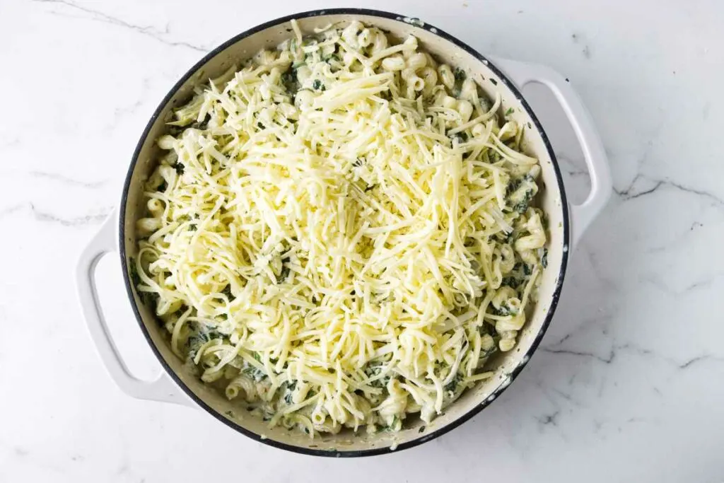 Topping the casserole with shredded cheese.