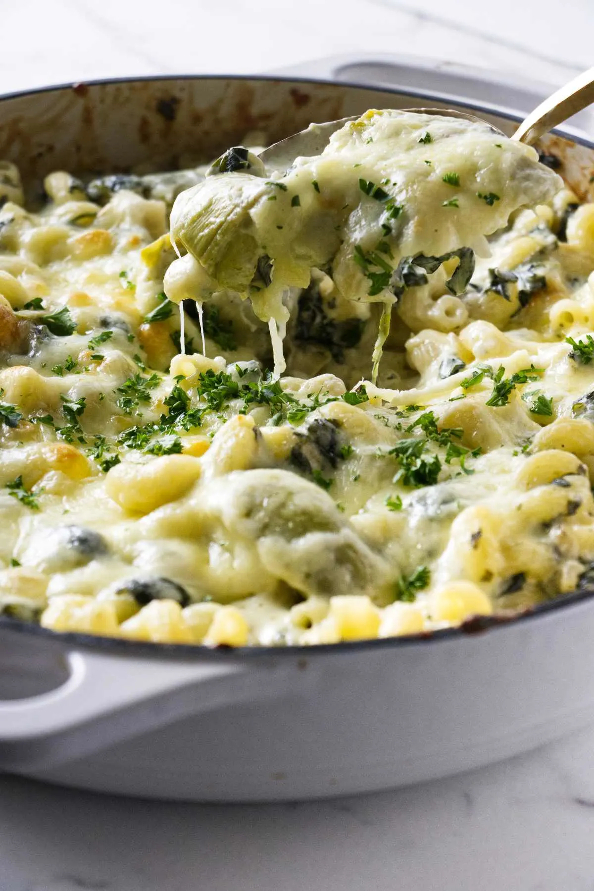 Scooping a serving of an artichoke pasta bake.