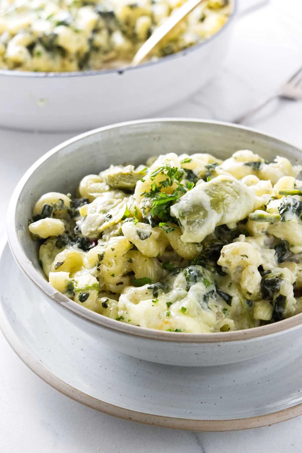 A bowl of pasta with a large skillet in the background.