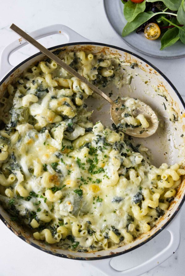 A spoon in a skillet filled with a pasta bake.