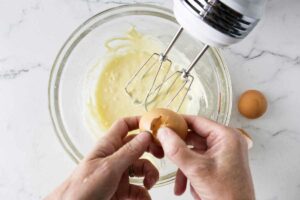 Adding eggs to muffin batter.