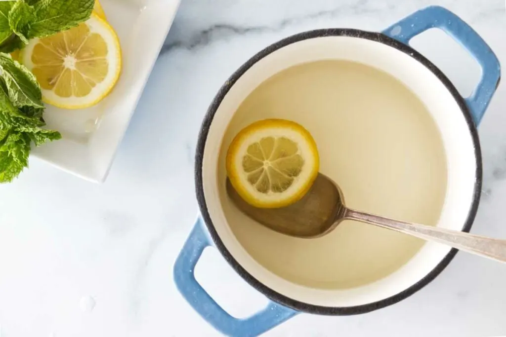 a saucepan with simple syrup, slices of lemon and fresh mint in the upper left corner.