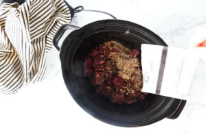 Sprinkling the contents of a packet of dry onion soup mix over beef stew meat.