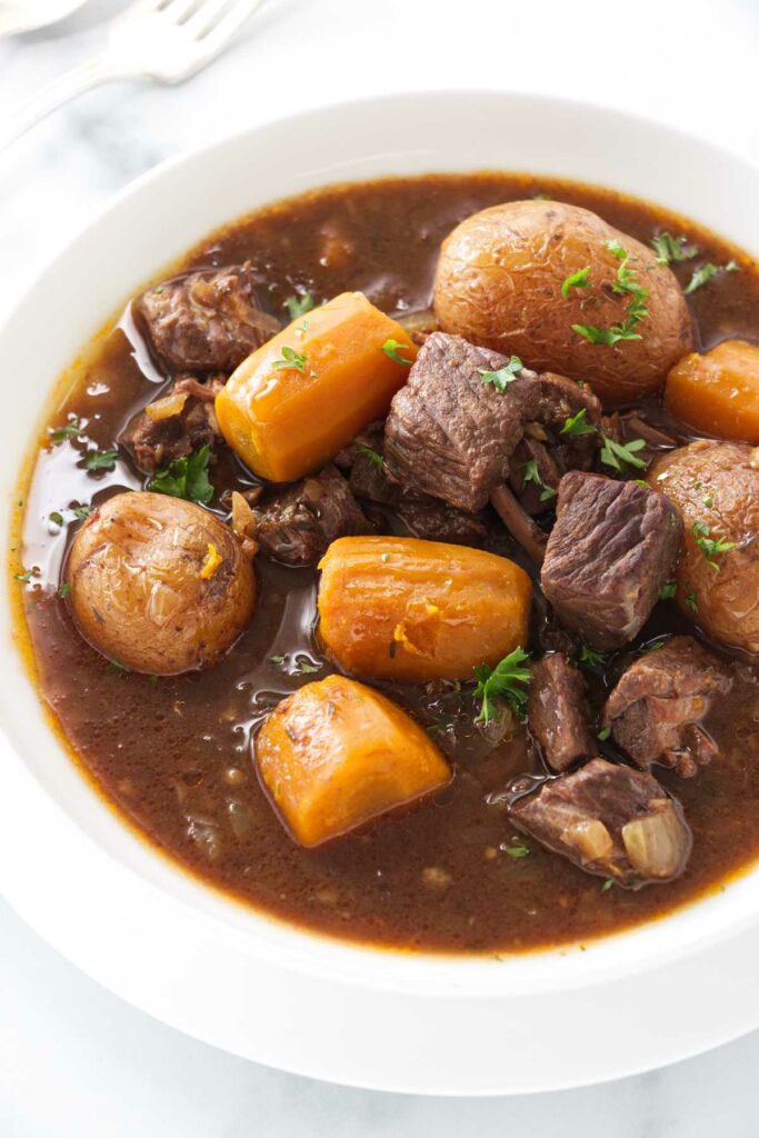 Carrots, potatoes and chunks of beef in a brown gravy sauce in a dish.