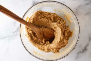 A bowl of cookie dough with a wooden spoon.