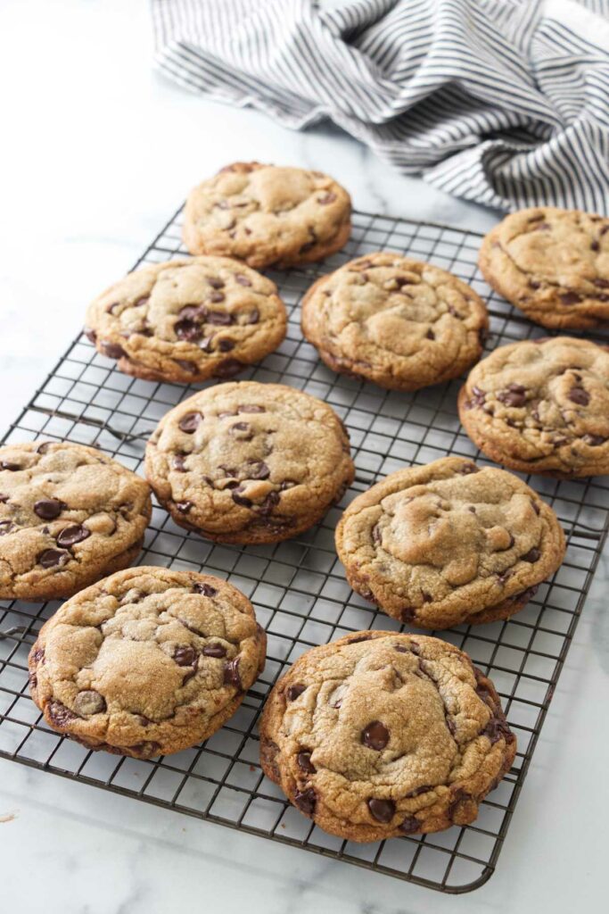 A wire cooling rack with giant cookies. A striped kitchen towel in the background.