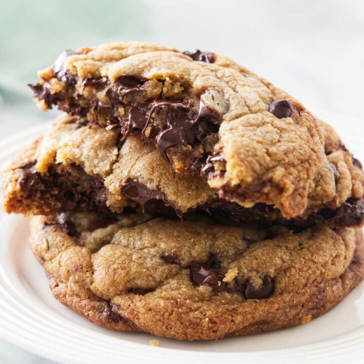 Two cookies on a plate, one cookie broken in half and stacked on the whole cookie.