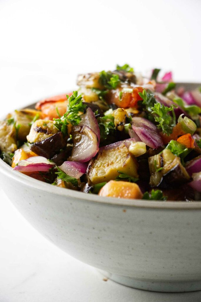 A serving bowl filled with a grilled eggplant salad.