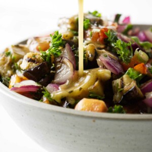 Pouring vinaigrette dressing over a salad.