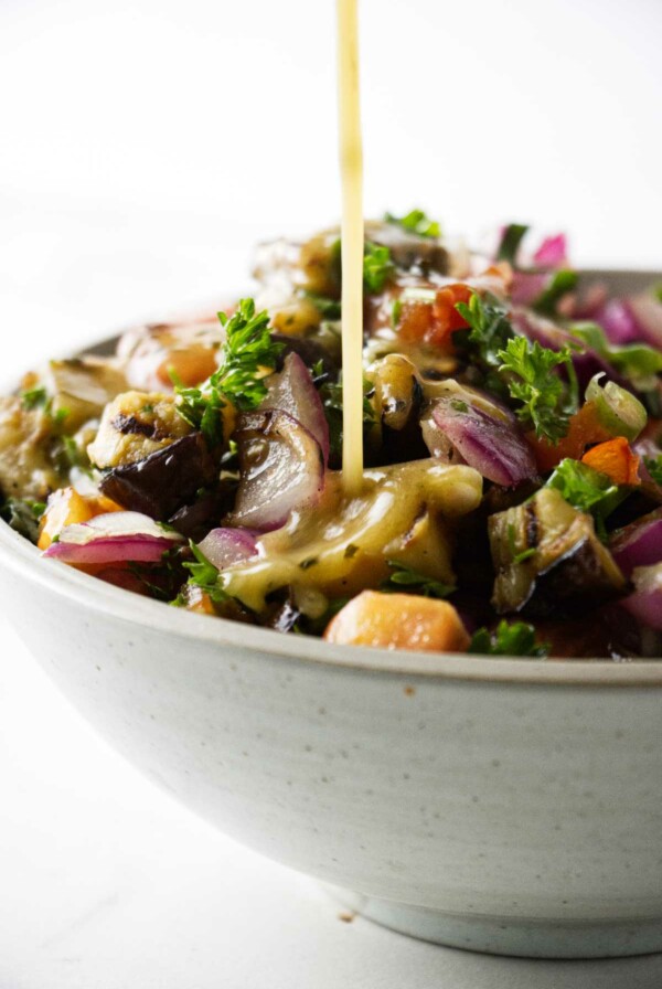 Pouring vinaigrette dressing over a salad.