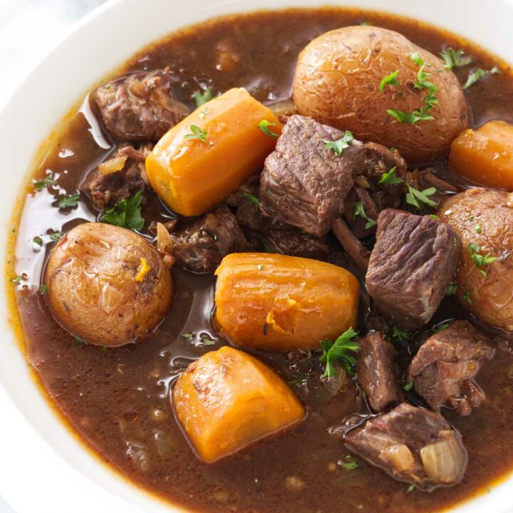 Carrots, potatoes and chunks of beef in a brown gravy sauce in a dish.