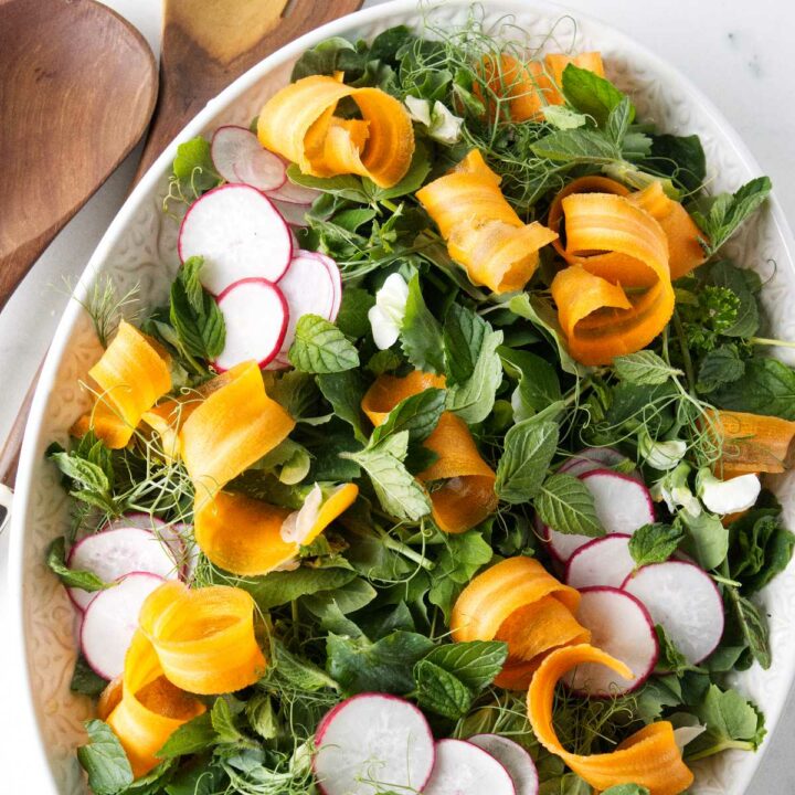 A serving bowl filled with a pea shoots salad.
