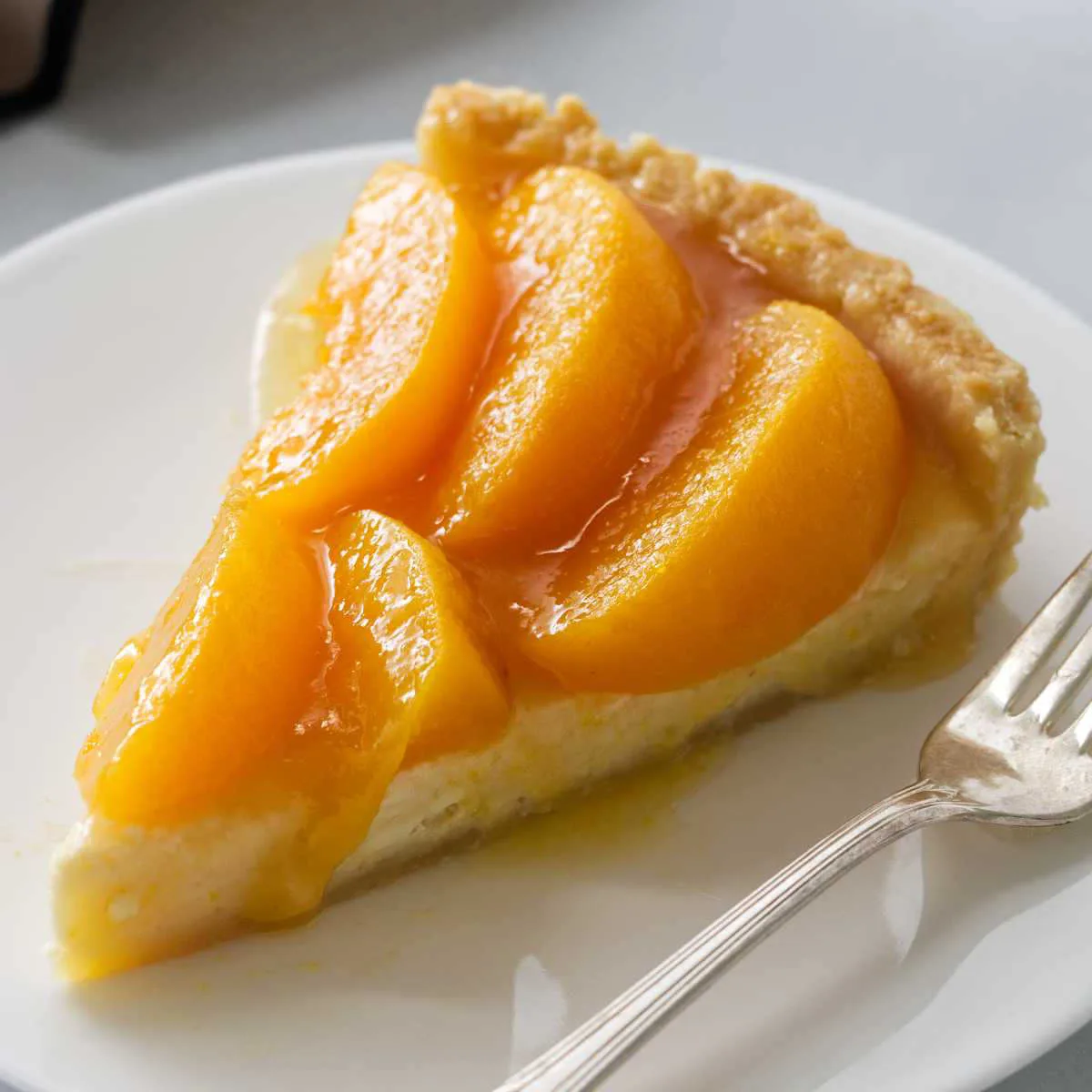 A slice of peach cream tart on a plate.