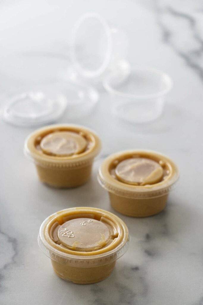 Miso butter portioned into small lidded containers. Two empty plastic containers and lids in the background.