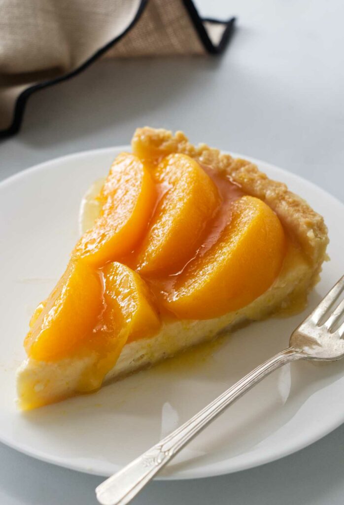 A serving of peach tart on a plate with a fork