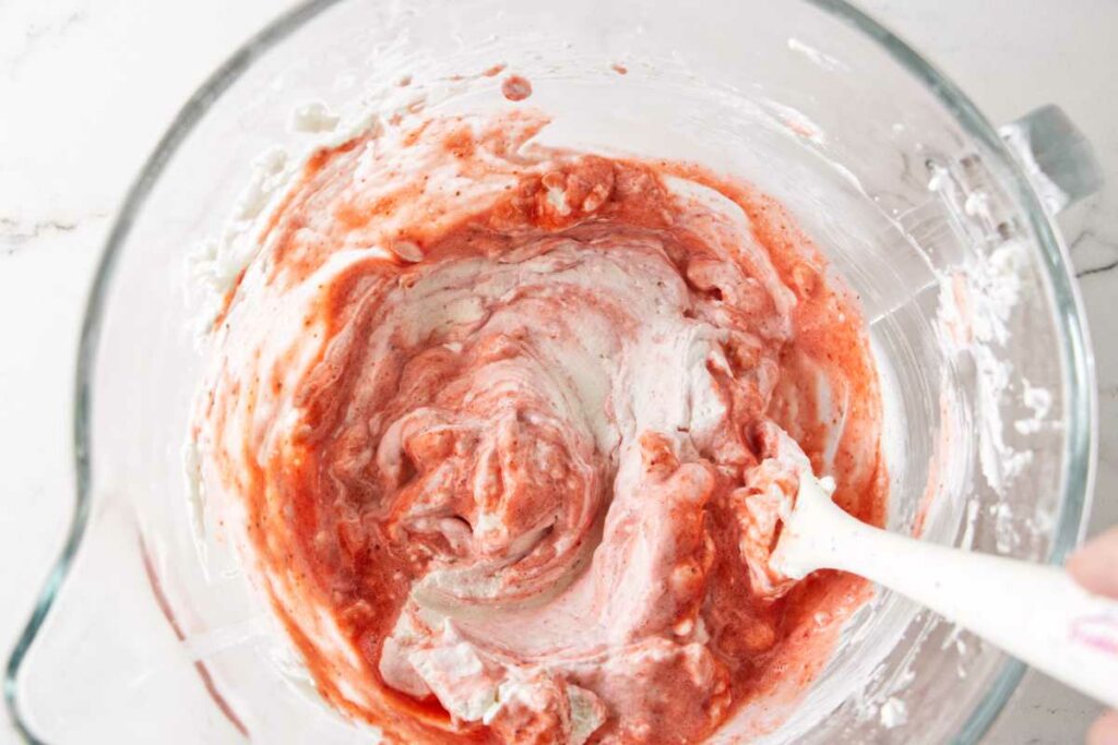 Folding strawberry puree into whipped cream.