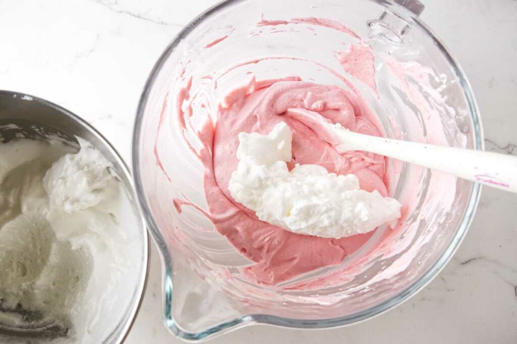 Folding meringue into strawberry whipped cream.