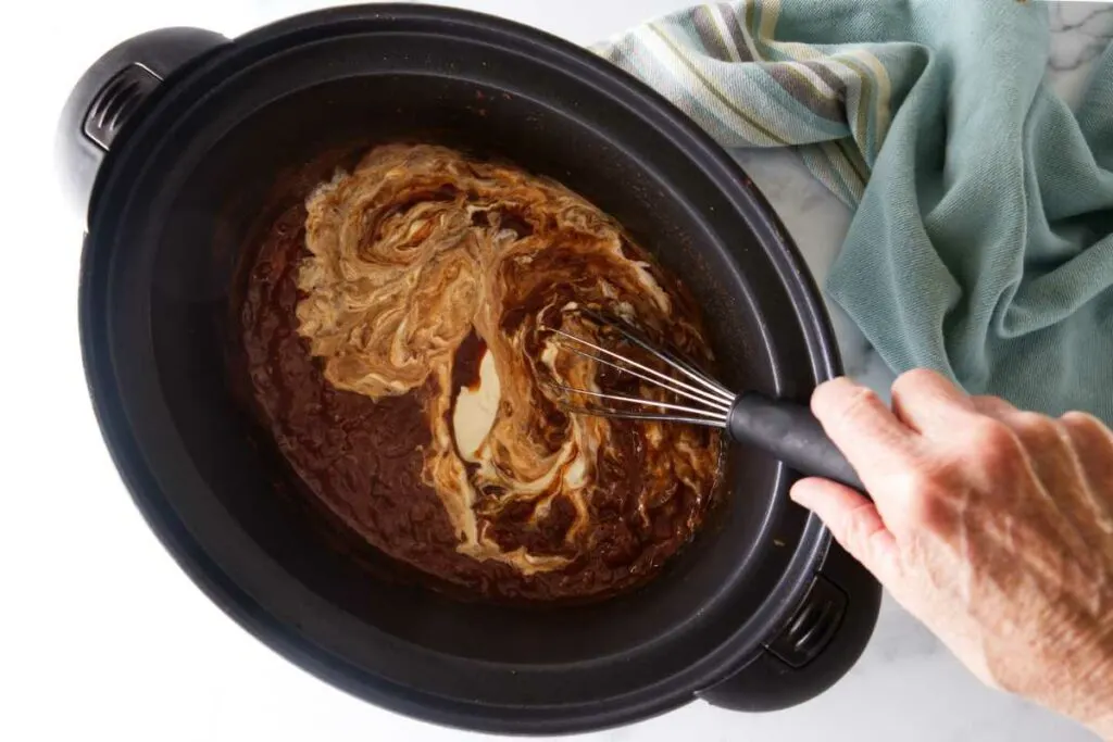 Whisking cream into a sauce.