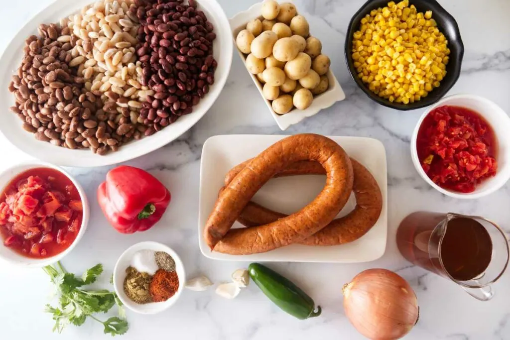 Ingredients for the recipe: Beans, potatoes, corn, spicy tomatoes, red bell pepper, sausage, tomatoes, broth, onion, jalepeno, garlic, spices, parsley.