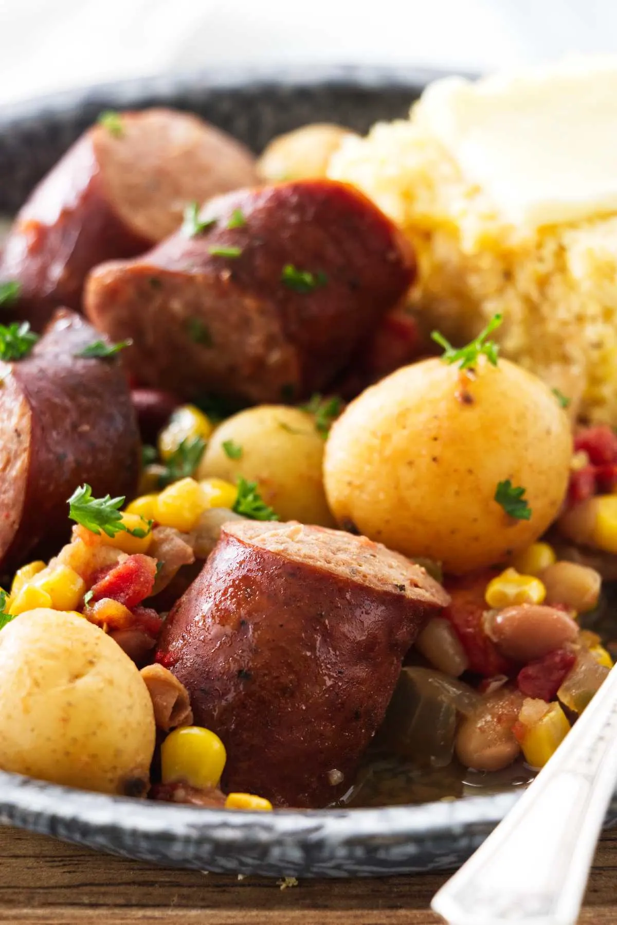 A plate of sausage, vegetables and cornbread.