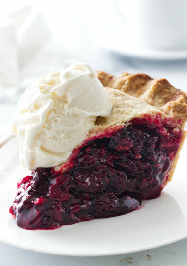 A plate with a slice of berry pie and a scoop of vanilla ice cream.