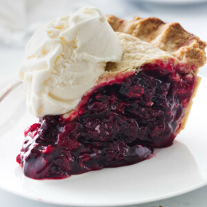 A plate with a slice of berry pie and a scoop of vanilla ice cream.