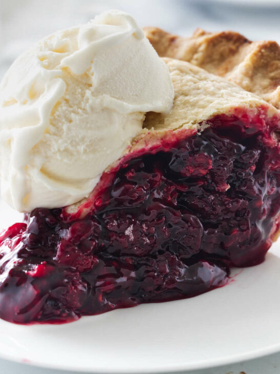A plate with a slice of berry pie and a scoop of vanilla ice cream.