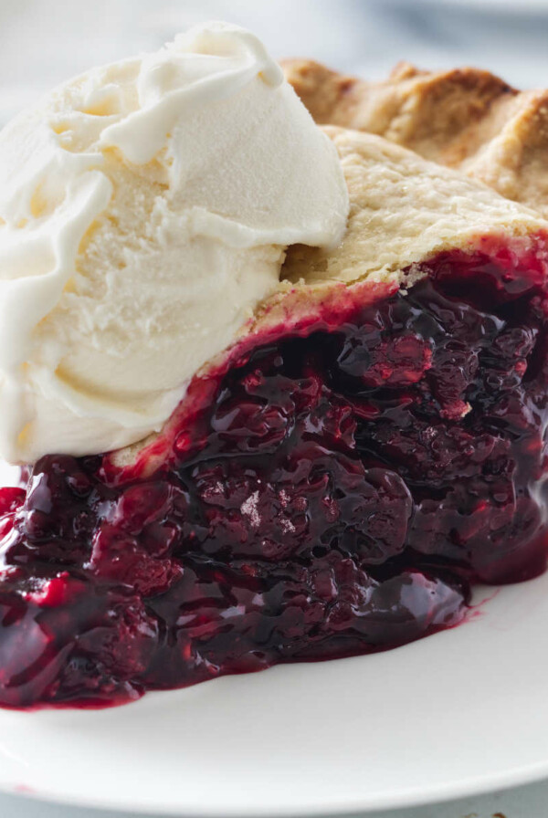 A plate with a slice of berry pie and a scoop of vanilla ice cream.