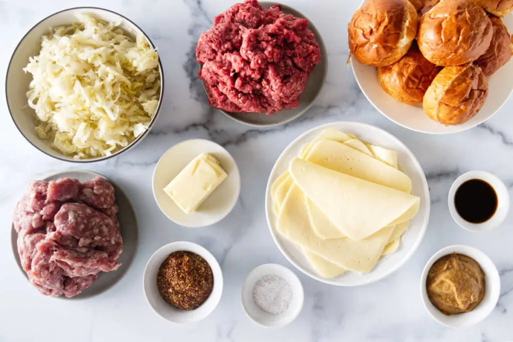 Ingredients used for bratwurst sliders: bratwurst, ground beef, sauerkraut, butter, mustard, salt, cheese, and dinner rolls.