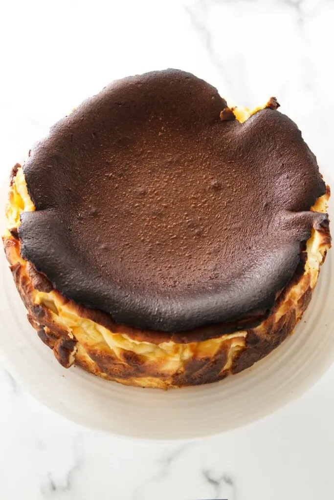 Top view of a Basque cheesecake sitting on a cake pedestal.