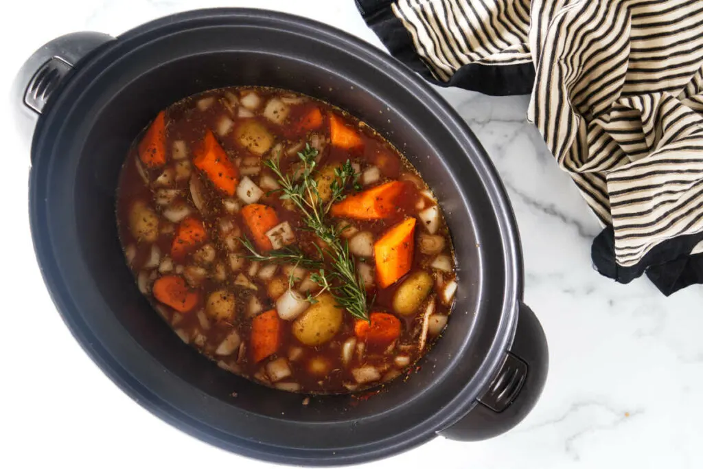 The slow cooker filled with the ingredients for the elk stew and ready to begin cooking.