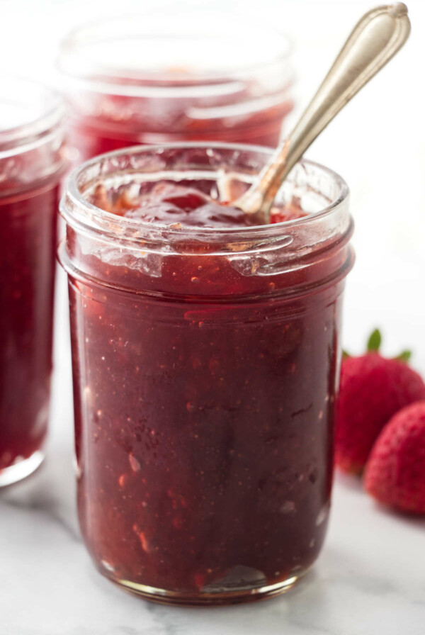 Homemade fresh strawberry jam in a mason jar with a spoon.