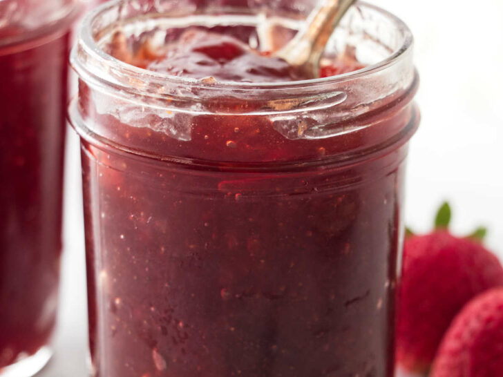 Homemade fresh strawberry jam in a mason jar with a spoon.