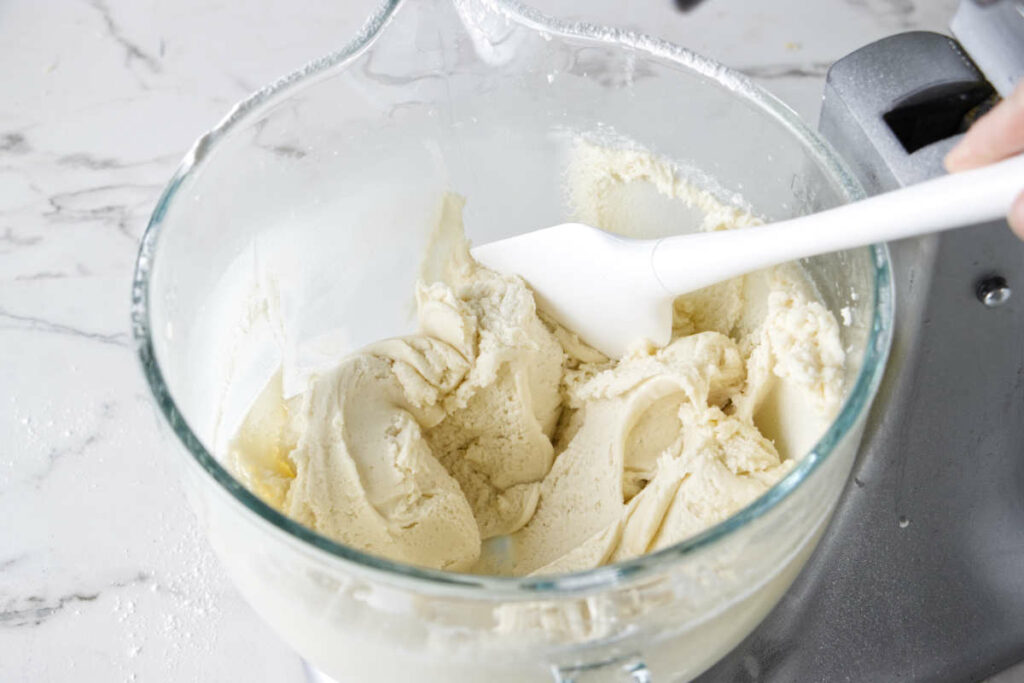 Thick cake batter in a mixing bowl after beating in sour cream and a portion of milk.