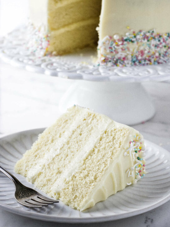 A slice slice of vanilla cake frosted with cream cheese frosting.