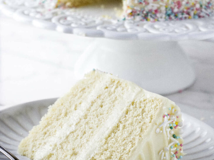 A slice slice of vanilla cake frosted with cream cheese frosting.