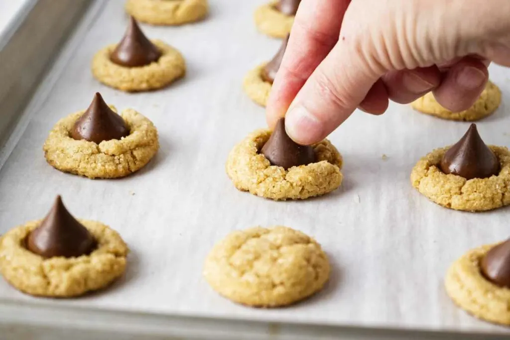 Pressing a Hershey's chocolate kiss into warm peanut butter cookies.