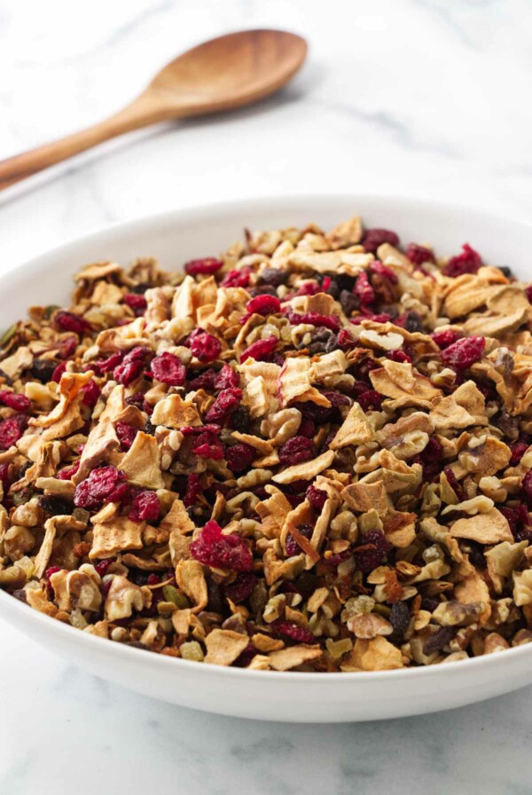 A large mixing bowl of ganola, a wooden mixing spoon in the background.