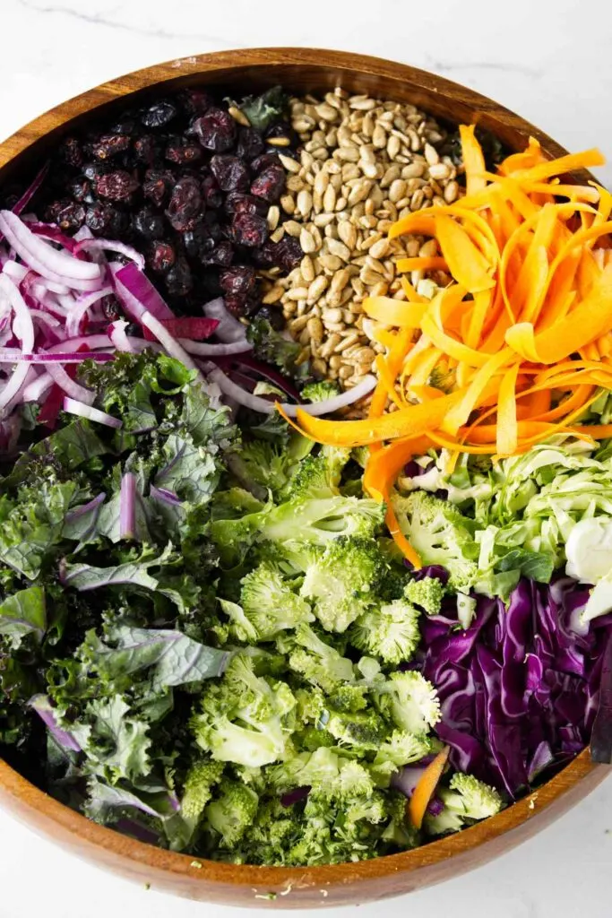 A large bowl filled with salad fixings for a kale broccoli salad.