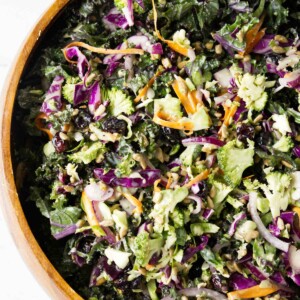 A wooden bowl filled with broccoli and kale salad.