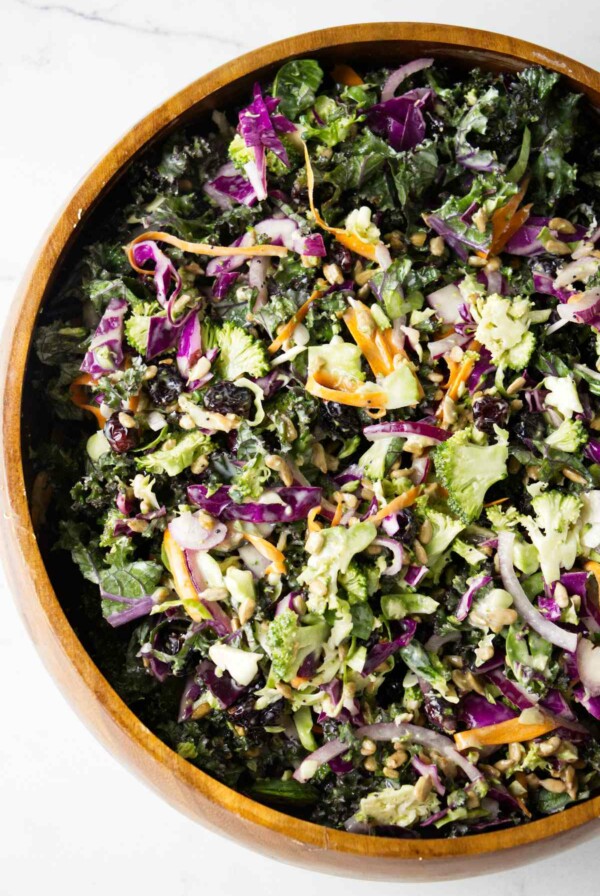 A wooden bowl filled with broccoli and kale salad.