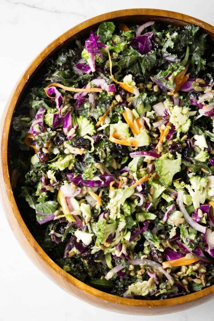 A wooden bowl filled with broccoli and kale salad.