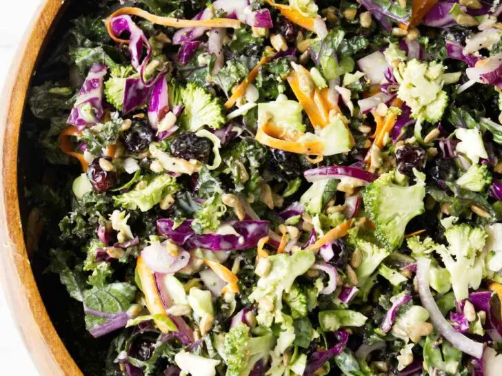 A wooden bowl filled with broccoli and kale salad.